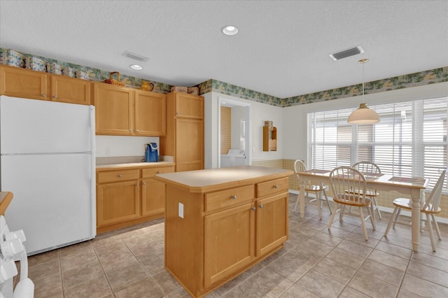 kitchen with a textured ceiling, pendant lighting, white refrigerator, light tile patterned floors, and a kitchen island