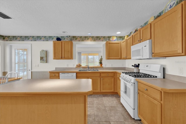 kitchen with a center island, white appliances, sink, light tile patterned floors, and a textured ceiling