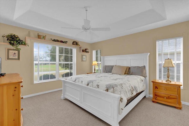 carpeted bedroom featuring ceiling fan and a raised ceiling