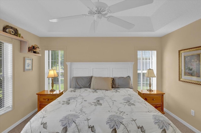 bedroom with carpet floors, a raised ceiling, and ceiling fan