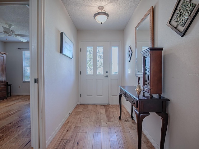 foyer entrance featuring ceiling fan, light hardwood / wood-style flooring, and a textured ceiling