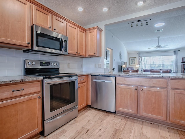 kitchen with decorative backsplash, stainless steel appliances, rail lighting, and a textured ceiling