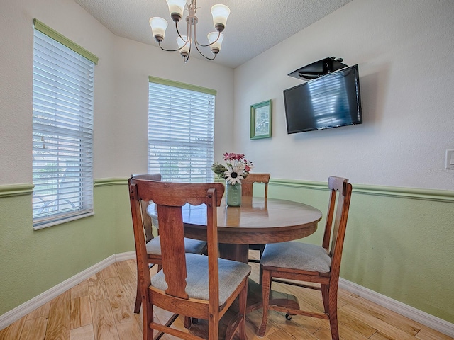 dining area featuring an inviting chandelier, light hardwood / wood-style floors, and a textured ceiling