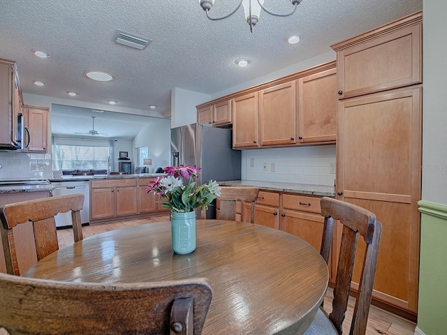 dining area with sink, ceiling fan with notable chandelier, light hardwood / wood-style flooring, and a textured ceiling