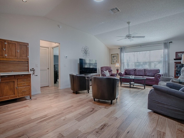 living room featuring lofted ceiling, a textured ceiling, light hardwood / wood-style flooring, and ceiling fan