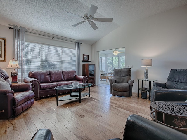 living room with ceiling fan, vaulted ceiling, a textured ceiling, and light wood-type flooring