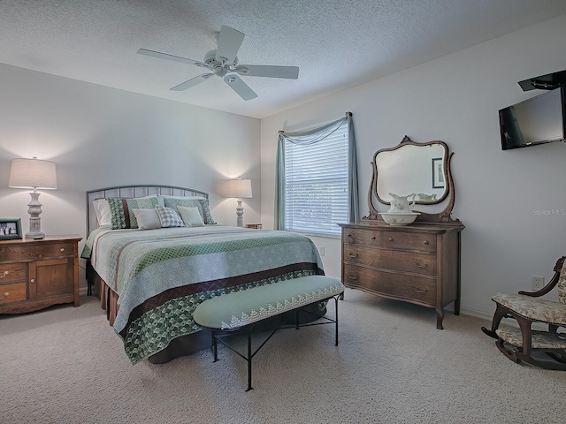 bedroom with ceiling fan, light carpet, and a textured ceiling