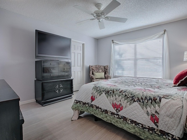 bedroom featuring ceiling fan, a textured ceiling, and light wood-type flooring