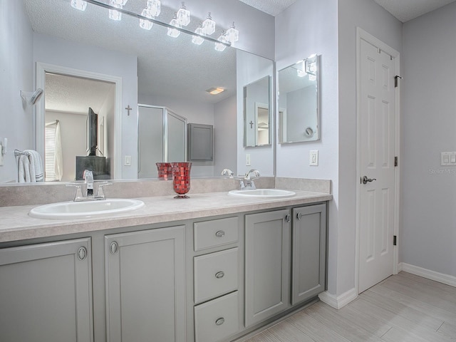 bathroom featuring vanity, an enclosed shower, and a textured ceiling