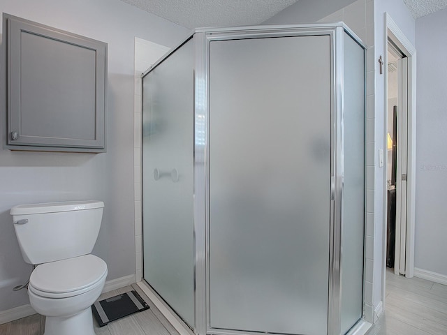 bathroom with toilet, an enclosed shower, and a textured ceiling