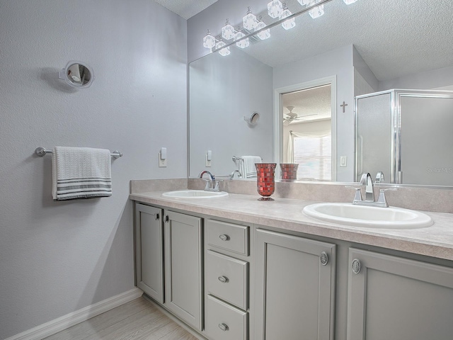 bathroom with a shower with door, vanity, and a textured ceiling