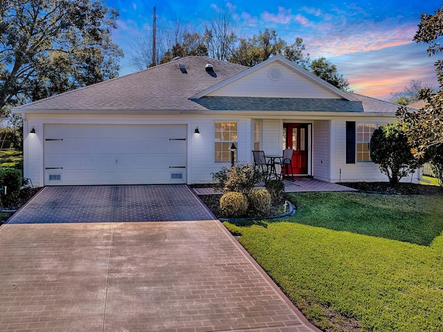 ranch-style house with a garage and a lawn