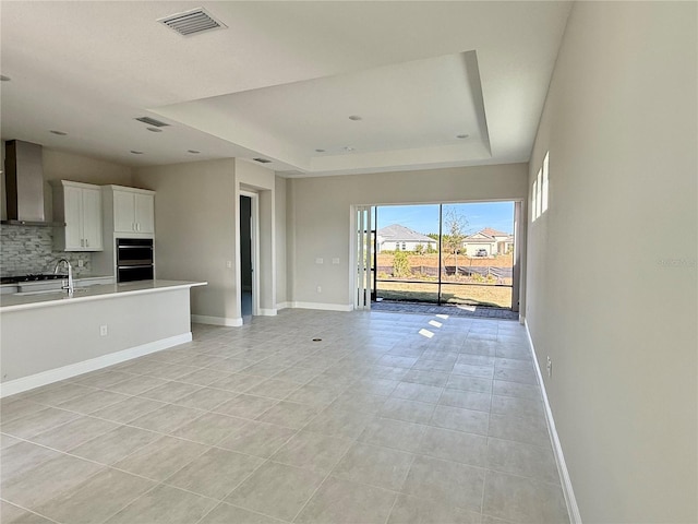 unfurnished living room with a tray ceiling and light tile patterned floors