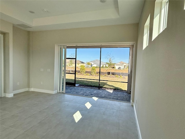 tiled empty room with a raised ceiling