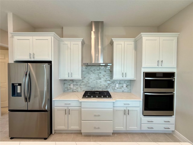 kitchen with white cabinetry, light stone countertops, wall chimney exhaust hood, stainless steel appliances, and backsplash