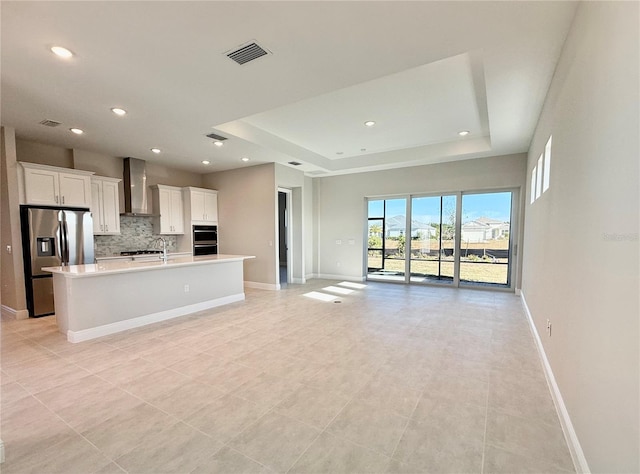 unfurnished living room with a tray ceiling and light tile patterned flooring