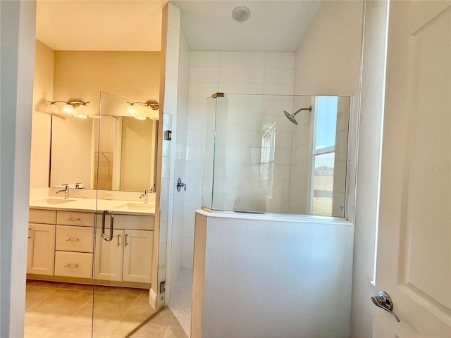 bathroom with tile patterned flooring, a tile shower, and vanity