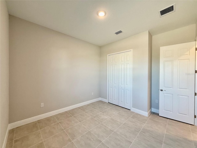 unfurnished bedroom with light tile patterned floors and a closet