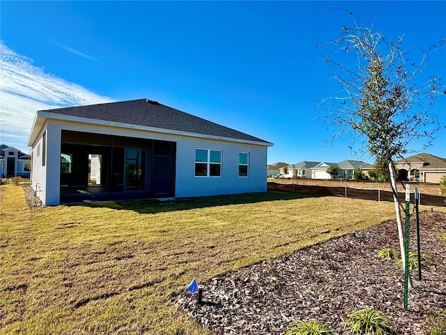 back of property with a lawn and a sunroom