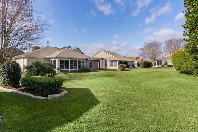 rear view of house featuring a sunroom and a lawn