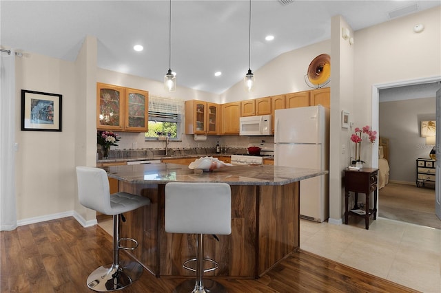 kitchen featuring tasteful backsplash, white appliances, dark stone counters, hanging light fixtures, and a kitchen island