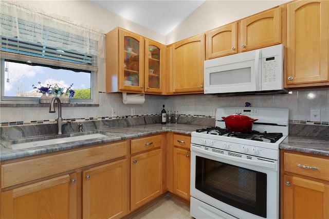 kitchen with tasteful backsplash, vaulted ceiling, sink, white appliances, and light tile patterned floors