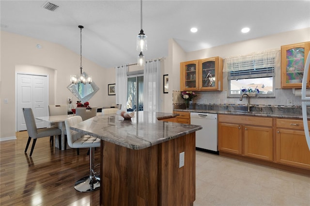 kitchen with decorative light fixtures, white dishwasher, vaulted ceiling, a chandelier, and sink