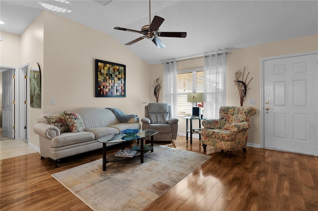 living room with lofted ceiling, ceiling fan, dark wood-type flooring, and a textured ceiling