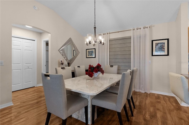 dining space featuring wood-type flooring and a notable chandelier