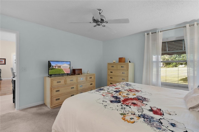 bedroom with a textured ceiling, ceiling fan, and light colored carpet