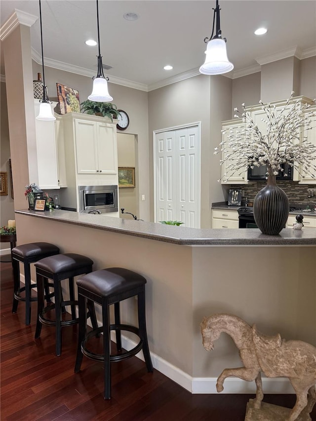 kitchen featuring ornamental molding, black appliances, pendant lighting, white cabinets, and dark hardwood / wood-style floors