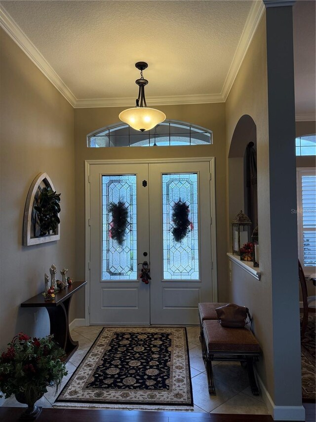 tiled entrance foyer featuring crown molding, plenty of natural light, and a textured ceiling