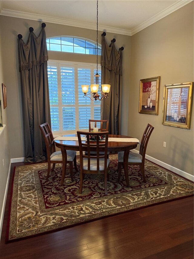 dining space with wood-type flooring, ornamental molding, and an inviting chandelier