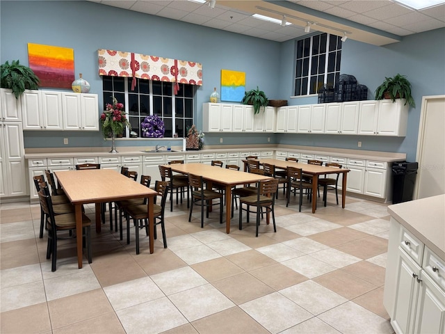 tiled dining room with sink, a drop ceiling, and track lighting