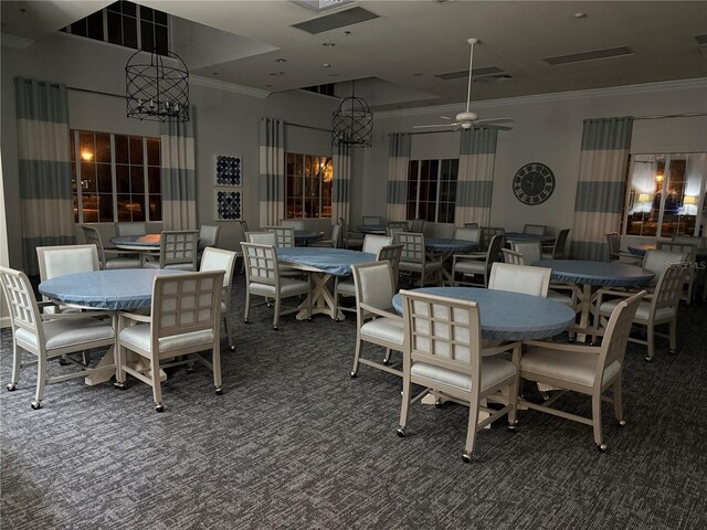 dining area with ceiling fan, dark carpet, and crown molding