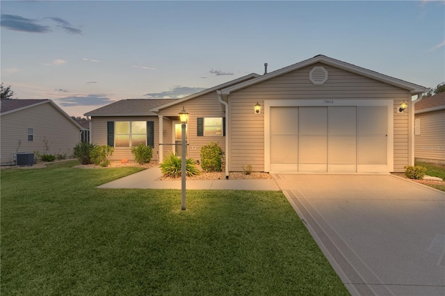 ranch-style home with a lawn, central AC unit, and a garage