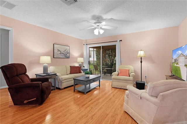 living room with ceiling fan, light hardwood / wood-style floors, and a textured ceiling