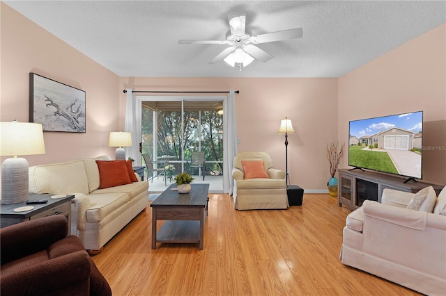 living room featuring ceiling fan, a textured ceiling, and light wood-type flooring