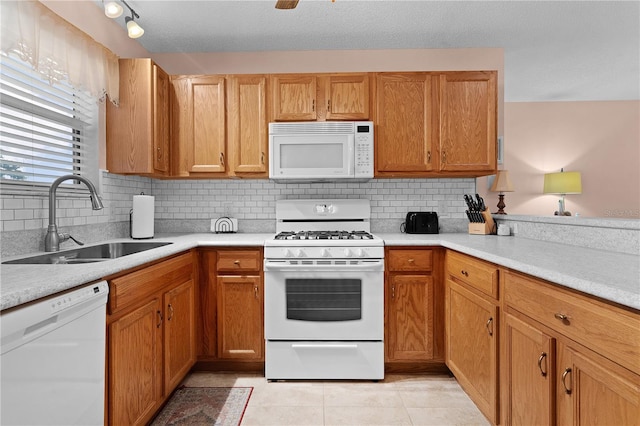 kitchen featuring tasteful backsplash, sink, light tile patterned flooring, and white appliances