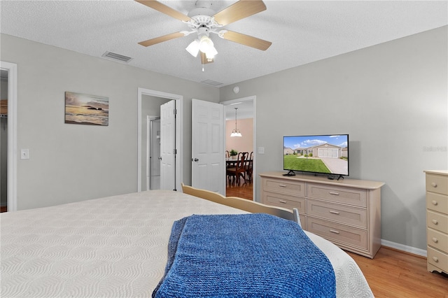 bedroom featuring ceiling fan, light wood-type flooring, and a textured ceiling