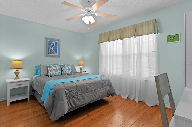 bedroom featuring hardwood / wood-style flooring, ceiling fan, and a textured ceiling