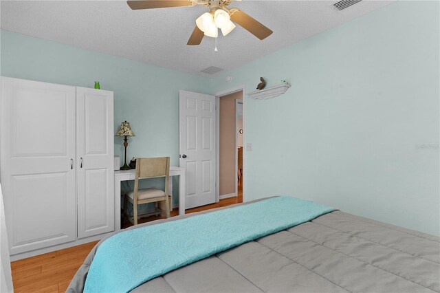 bedroom with ceiling fan, light wood-type flooring, a textured ceiling, and a closet