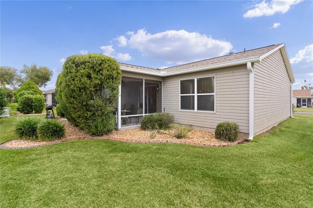 rear view of house featuring a yard and a sunroom