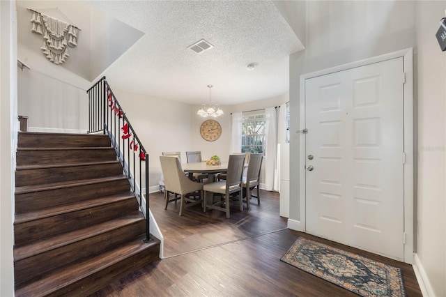 entrance foyer featuring dark wood-type flooring, an inviting chandelier, and a textured ceiling