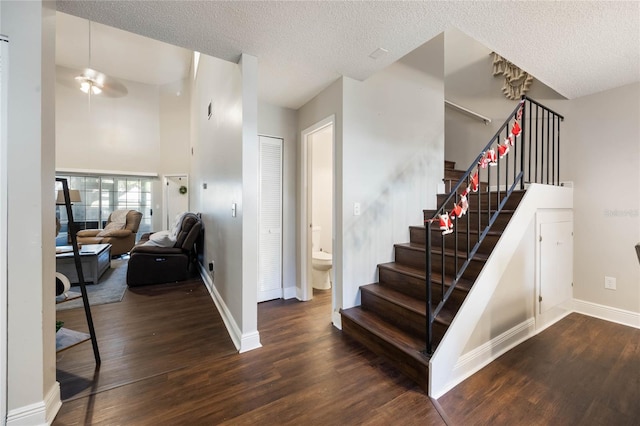 stairway featuring ceiling fan, wood-type flooring, and a textured ceiling