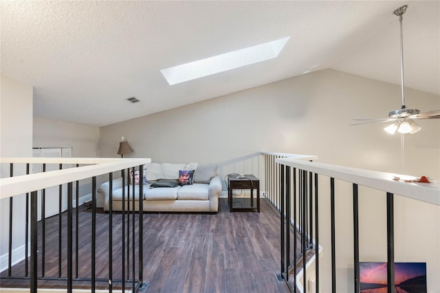 hall featuring lofted ceiling with skylight, dark hardwood / wood-style floors, and a textured ceiling