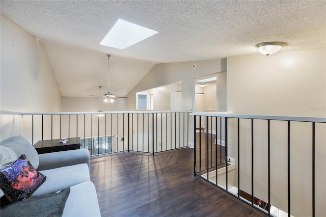 living area with lofted ceiling with skylight, dark hardwood / wood-style floors, and a textured ceiling