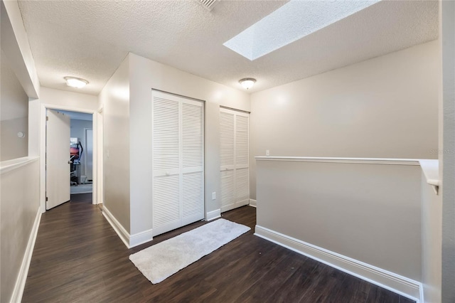 hallway with dark hardwood / wood-style flooring, a skylight, and a textured ceiling