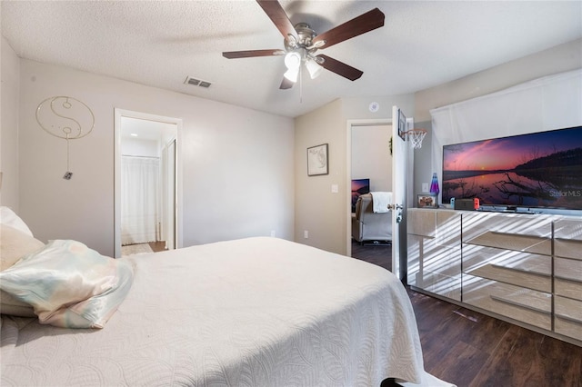 bedroom with ceiling fan, a textured ceiling, and dark hardwood / wood-style flooring