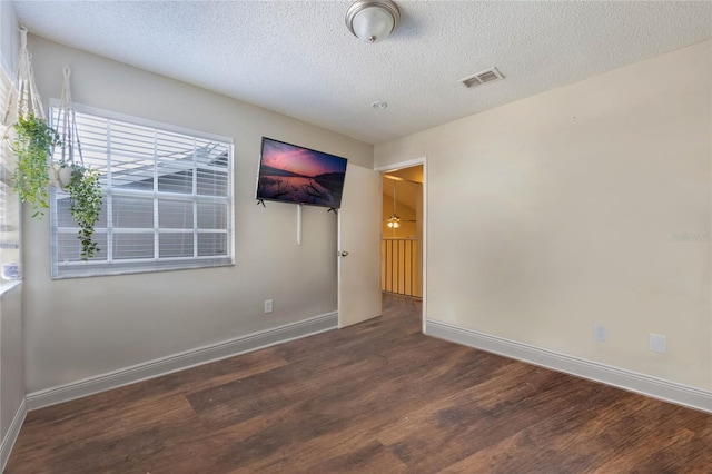 empty room featuring dark hardwood / wood-style flooring and a textured ceiling